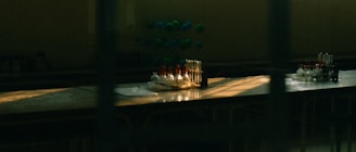 A dimly lit laboratory table with an arrangement of test tubes, some filled with liquid in varied colors. There is also a molecular model in the background. Sunlight through the window casts dramatic shadows and highlights on the surface.