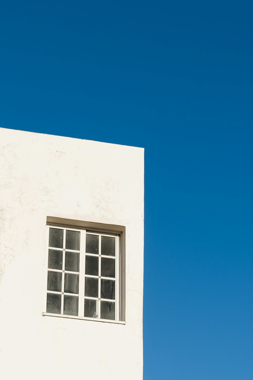 a white building with a window and a blue sky in the background