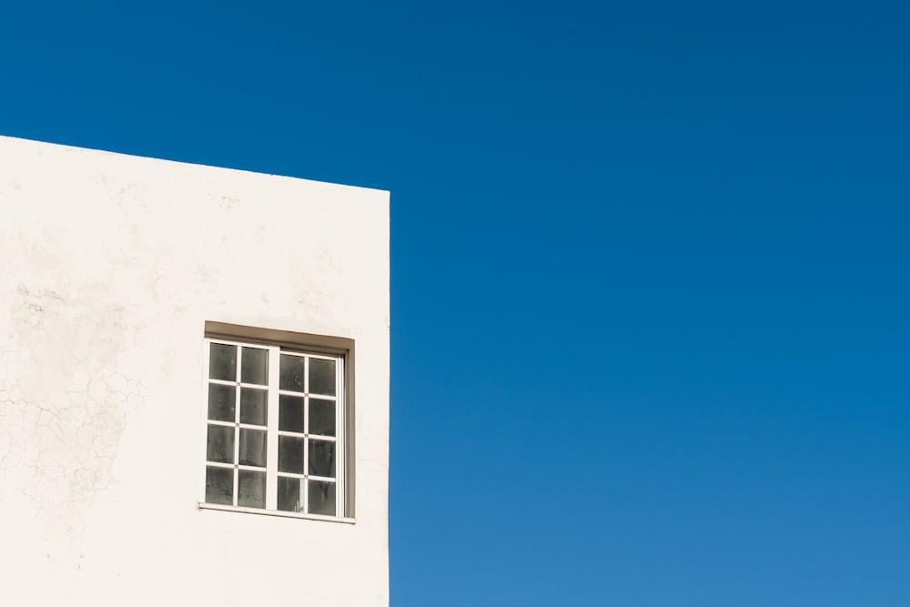 ein weißes Gebäude mit einem Fenster und einem Himmelshintergrund