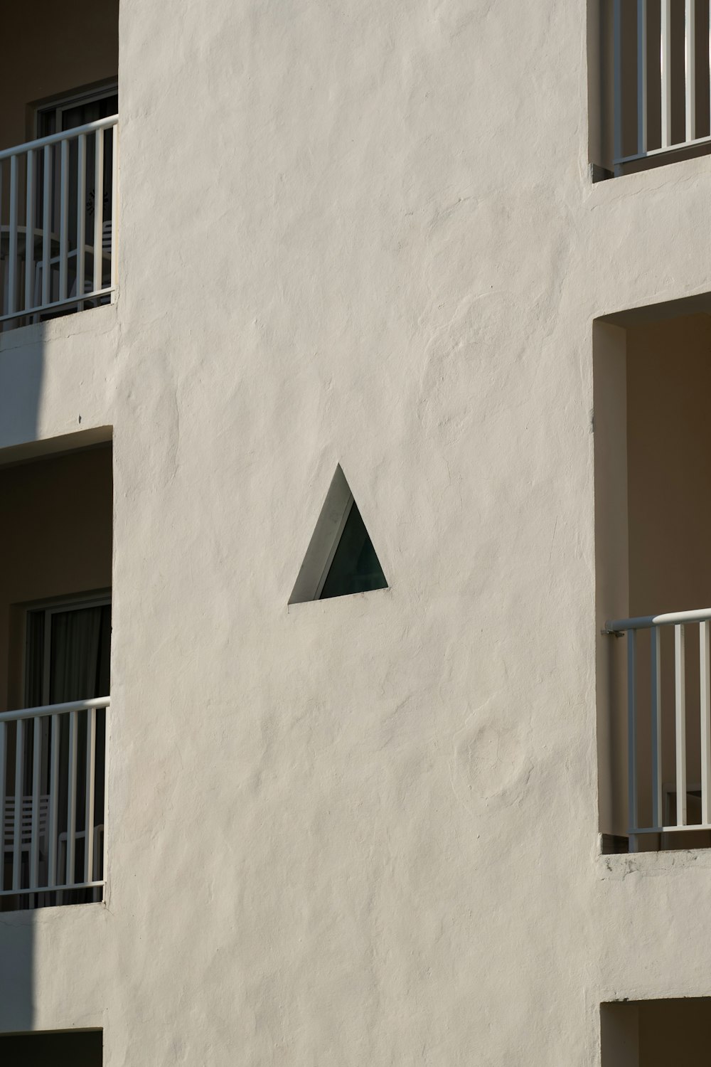 a white building with a triangular window and balconies