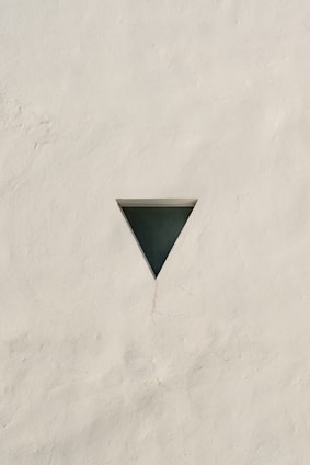 a white wall with a triangle shaped window