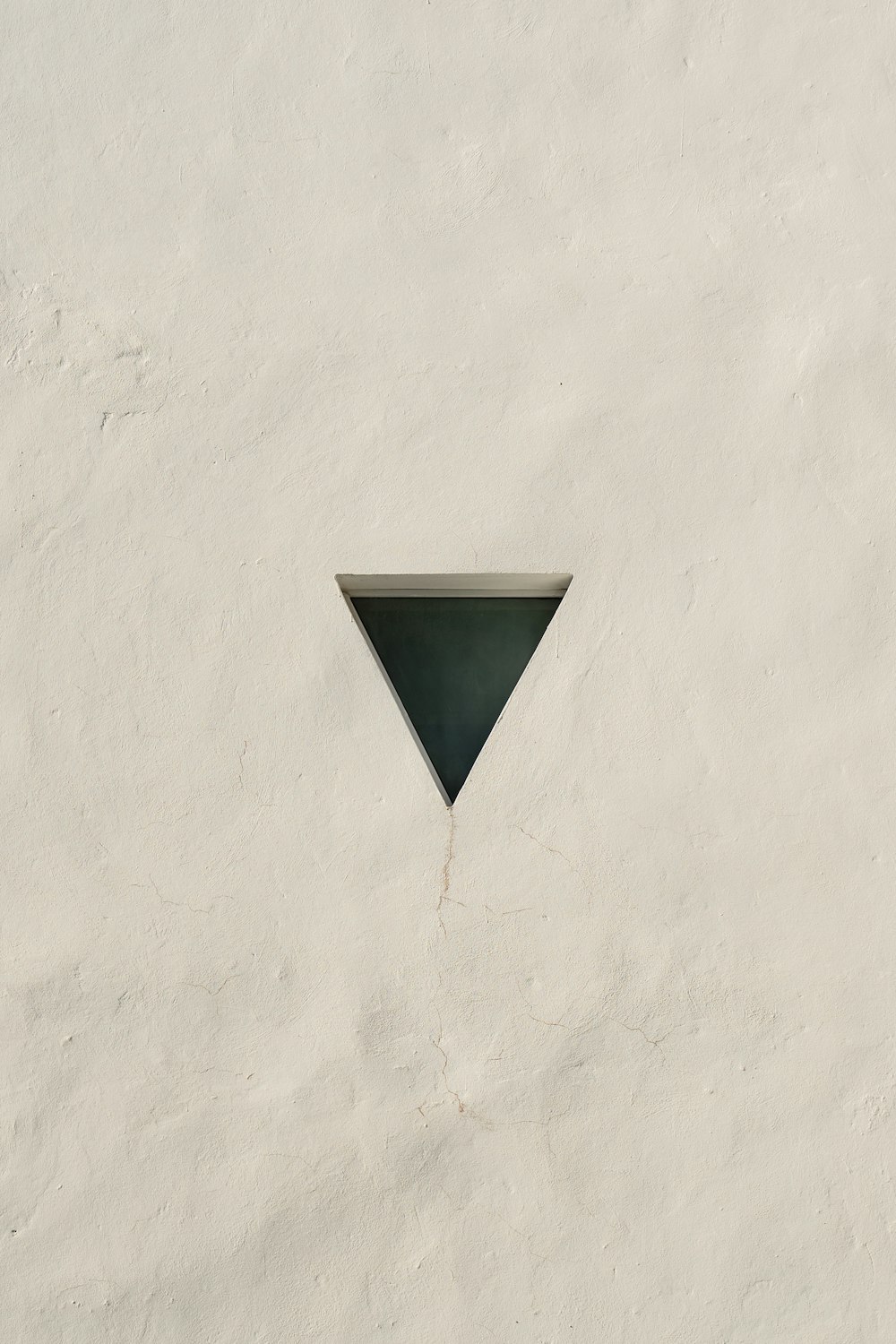 a white wall with a triangle shaped window