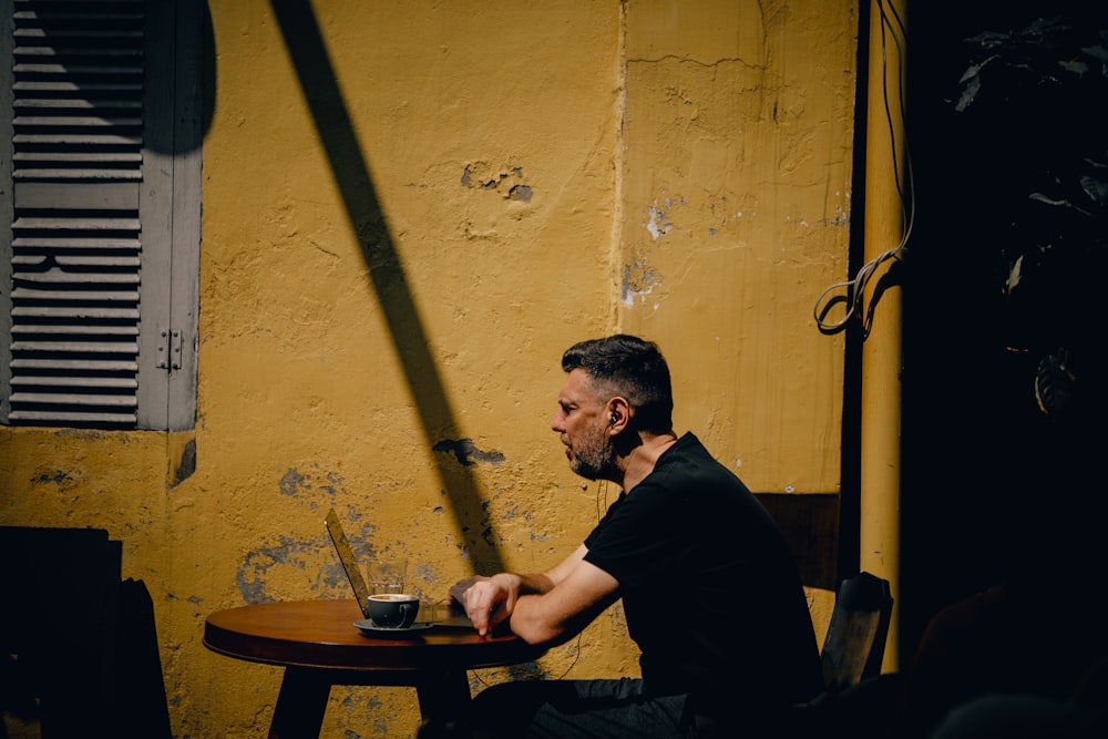 a man sitting at a table in front of a yellow wall