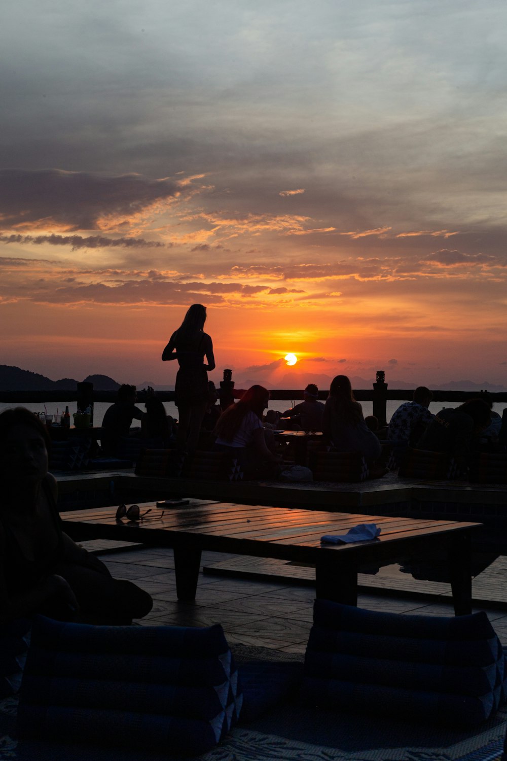 a group of people sitting at a table watching the sun set