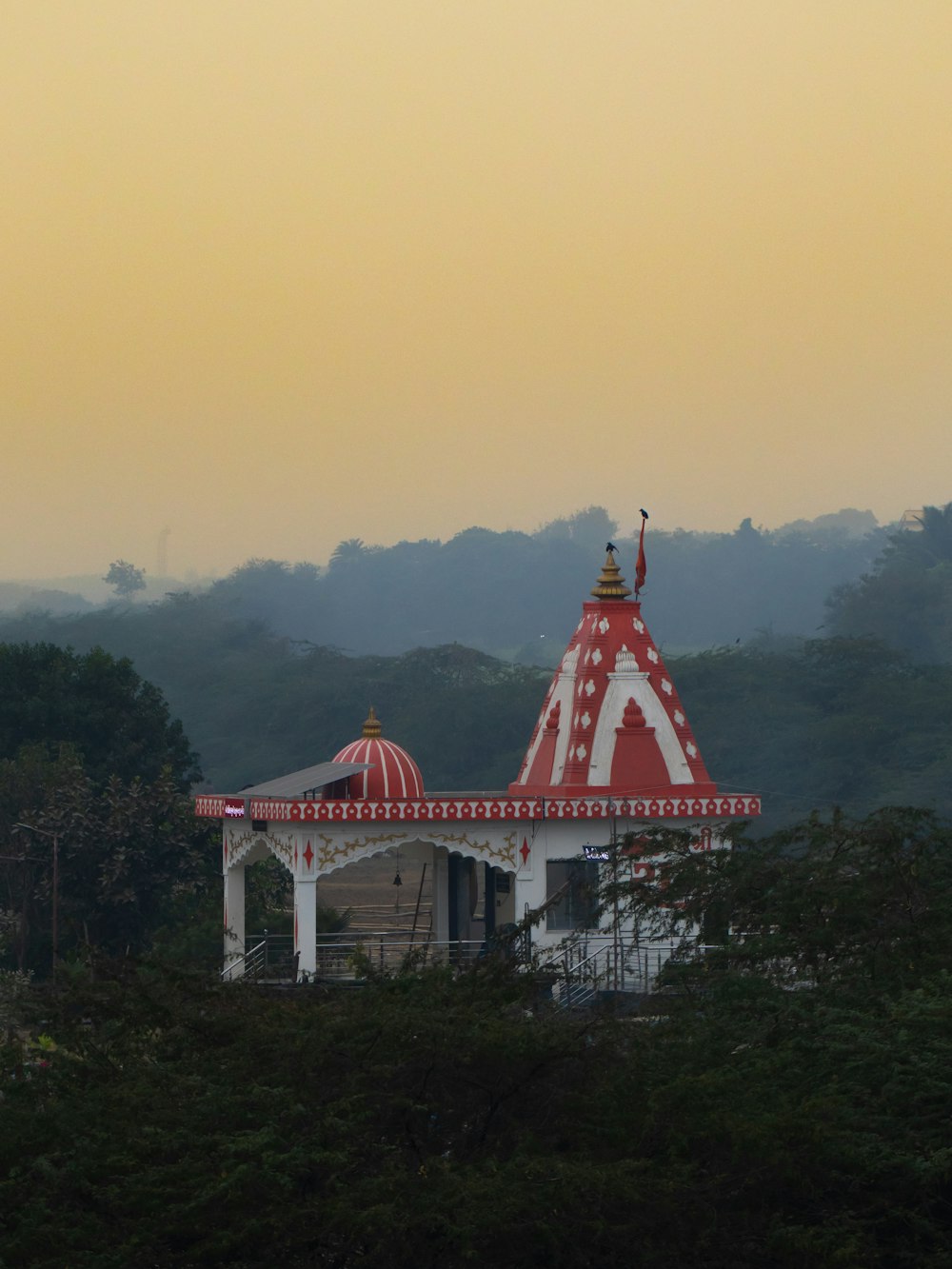 a red and white gazebo in the middle of a forest