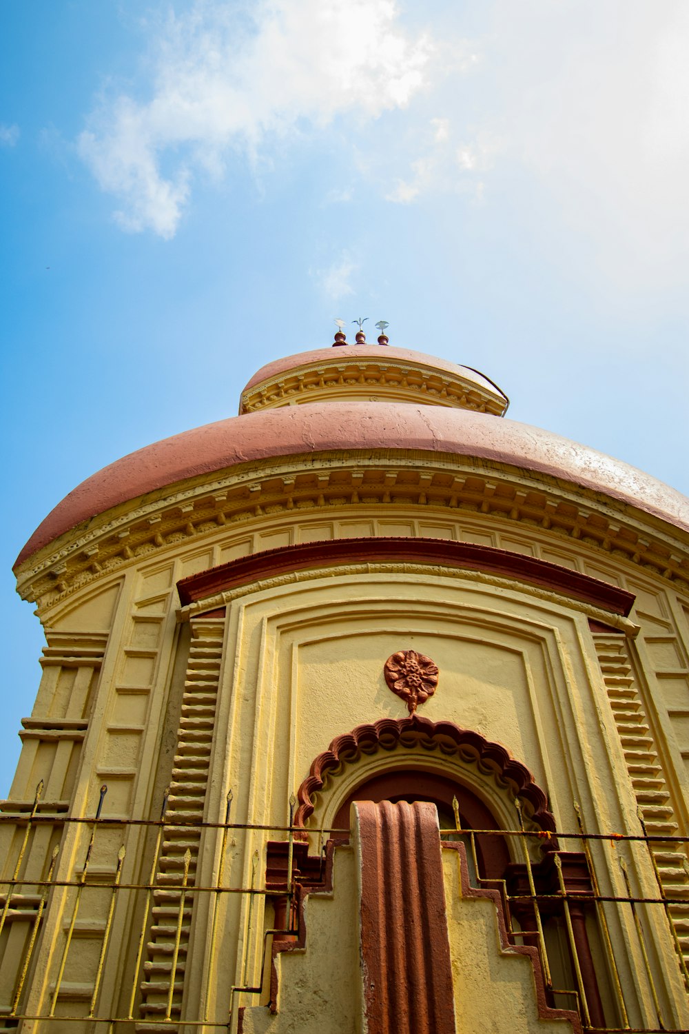 a yellow building with a red roof and a blue sky