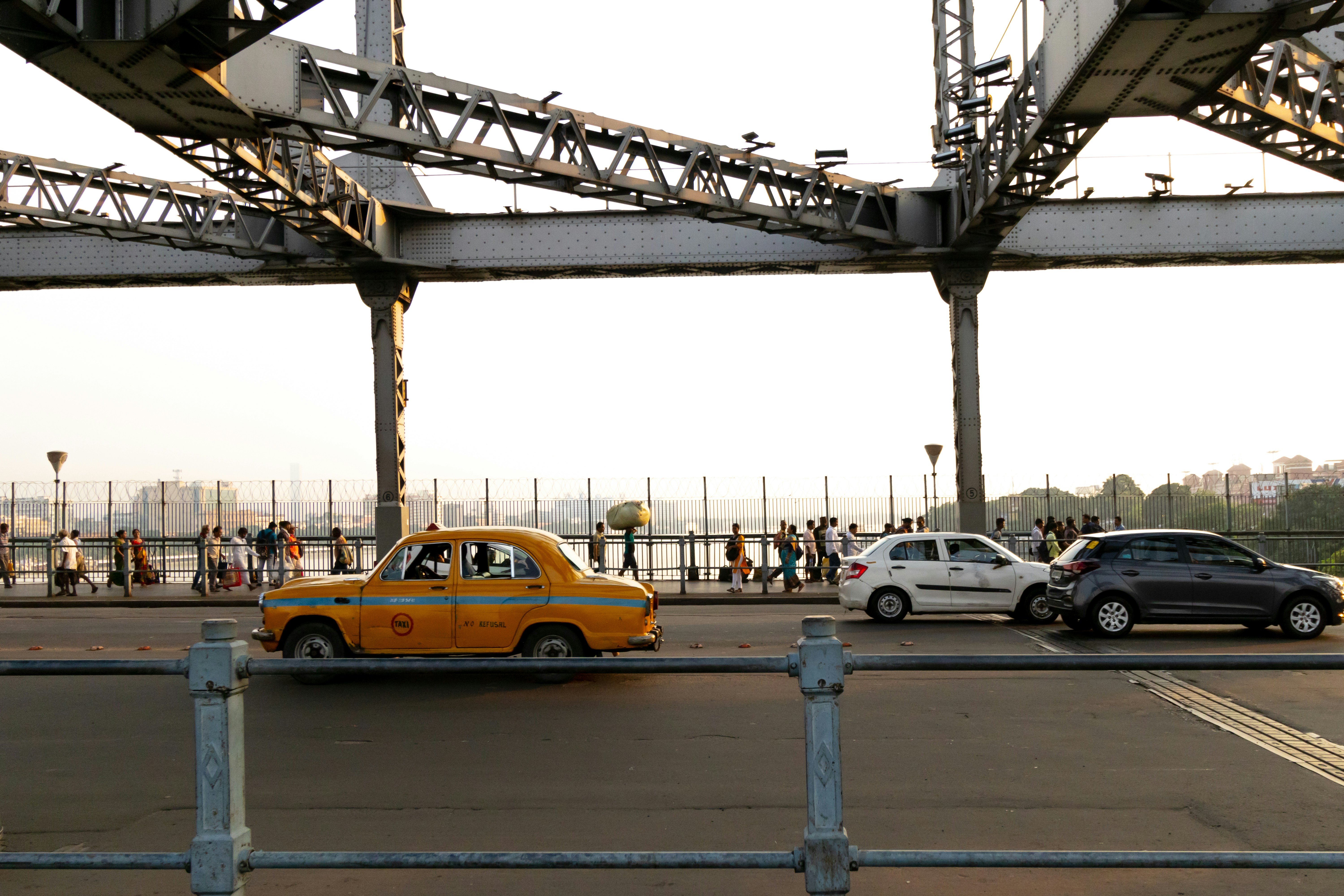 Un taxi amarillo conduciendo por una calle al lado de un puente