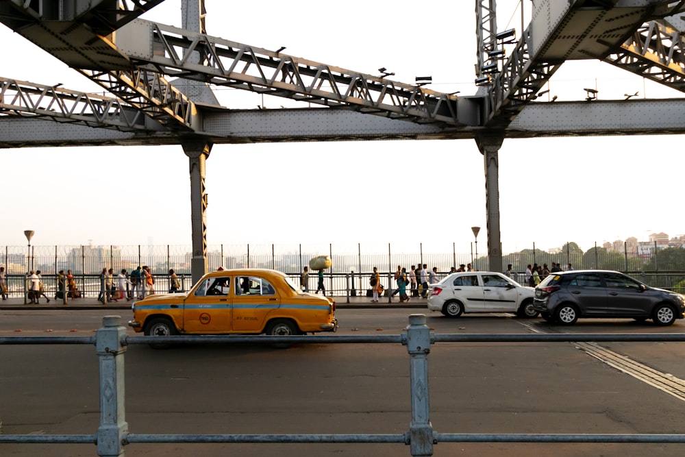a yellow taxi cab driving down a street next to a bridge