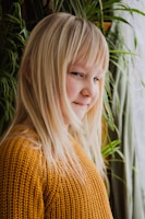 Editorial shot of a child wearing a soft beige cashmere sweater in a sunlit minimalist room.