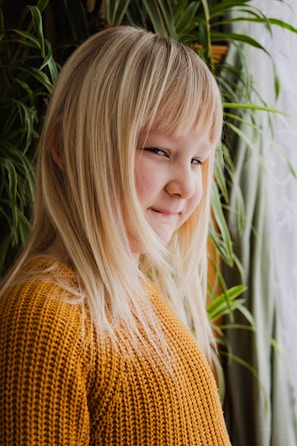 Editorial shot of a child wearing a soft beige cashmere sweater in a sunlit minimalist room.