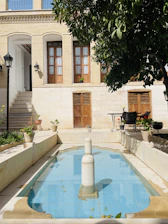 Traditional riad courtyard with tiled pool and lush greenery under warm sunlight.