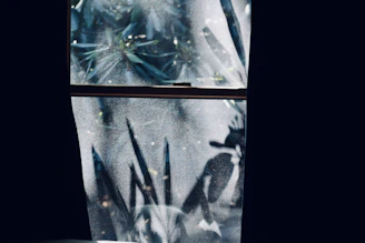 Bathroom window featuring delicate etched glass film, providing privacy while allowing light.