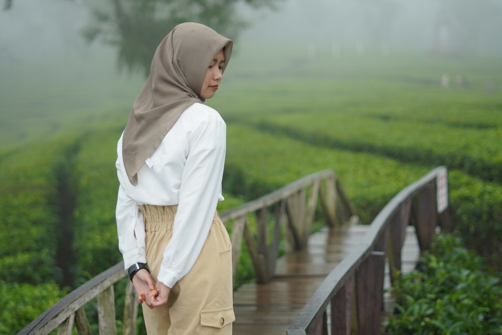 a woman in a hijab standing on a bridge