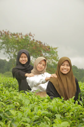 three women in hijabs are sitting in a field