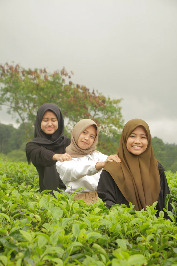 three women in hijabs are sitting in a field