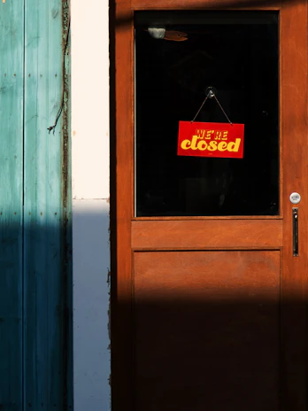 A closed sign hanging on a rustic wooden door with soft evening light.