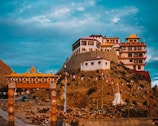 A serene Buddhist monastery perched on a rocky hill, with colorful prayer flags fluttering in the wind.