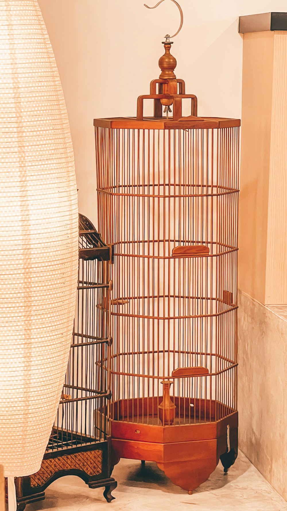 a bird cage sitting on top of a table next to a lamp