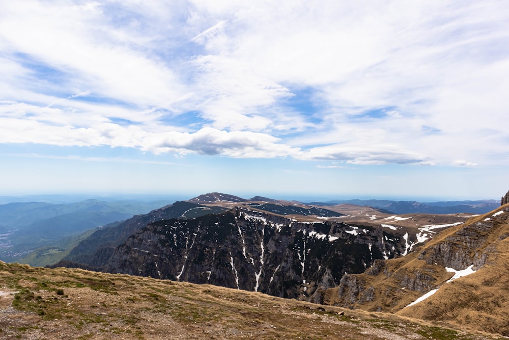 a man standing on top of a mountain next to a lush green hillside