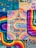 A collection of vibrant, multicolored drawings featuring abstract patterns and shapes. The central piece showcases dynamic, curved lines with a rainbow spectrum, surrounded by other artworks with similar vivid hues and whimsical designs.