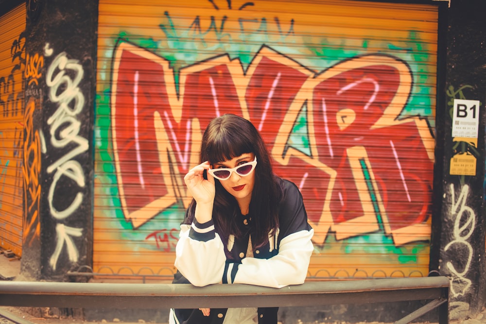 Une femme assise sur un banc devant un mur couvert de graffitis