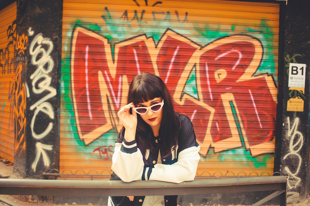 a woman sitting on a bench in front of a graffiti covered wall