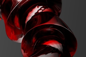 A close-up view of a glossy, abstract red and black structure with fluid-like curves and reflective surfaces, suggesting a modern and artistic design.