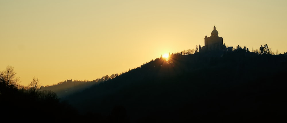Eine Kirche auf einem Hügel mit der untergehenden Sonne im Hintergrund