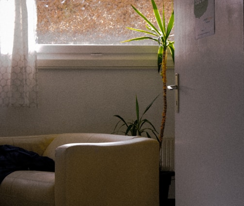 A softly lit room with a cozy armchair next to a window showing a peaceful garden.