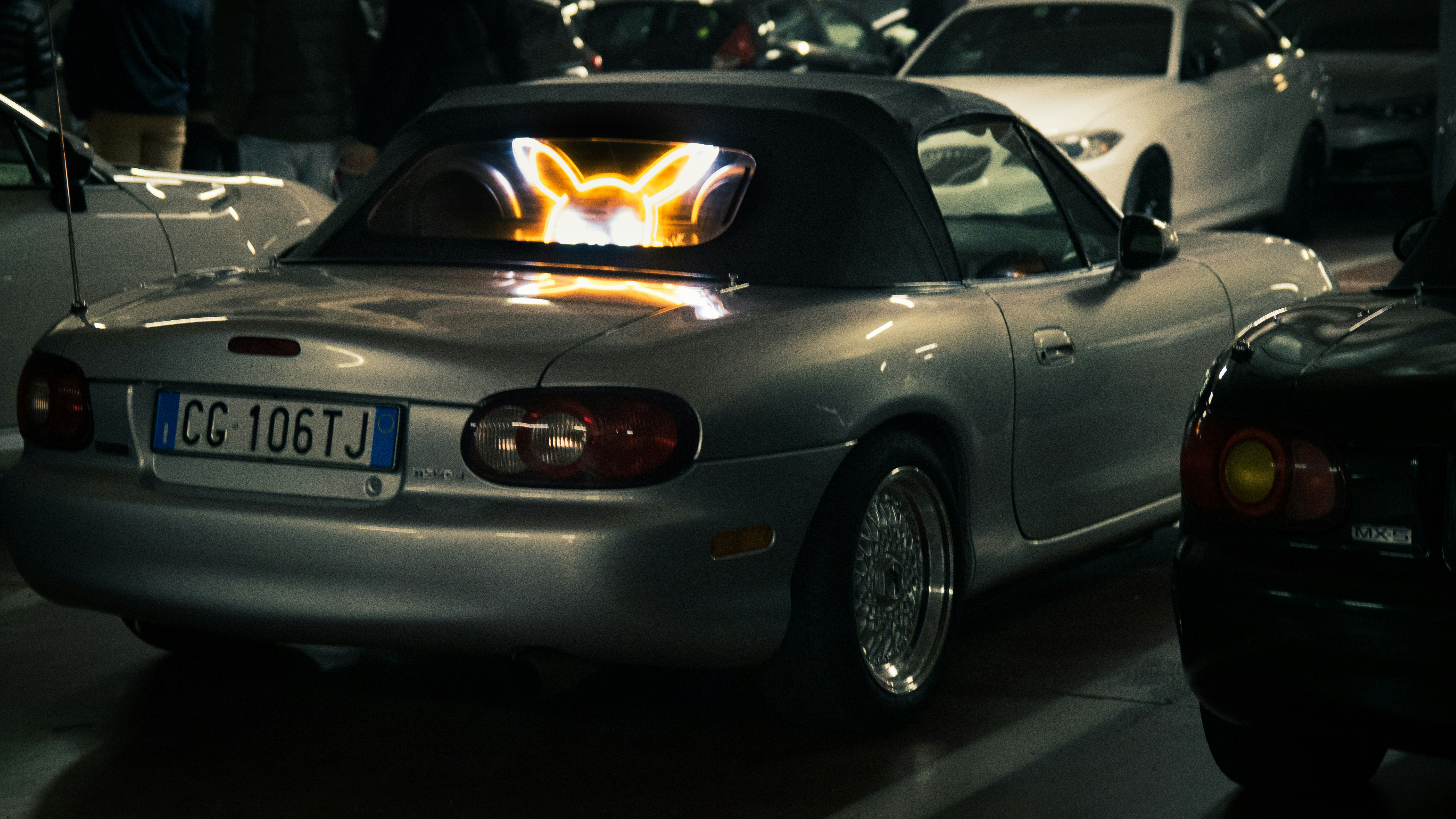 a silver sports car driving down a street at night
