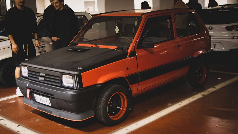 A group of people standing around a small car photo – Free Tuning