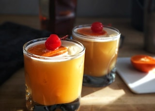 a couple of glasses filled with drinks on top of a table