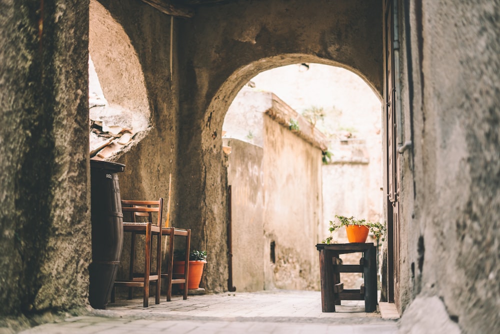 a narrow alley way with a chair and potted plants