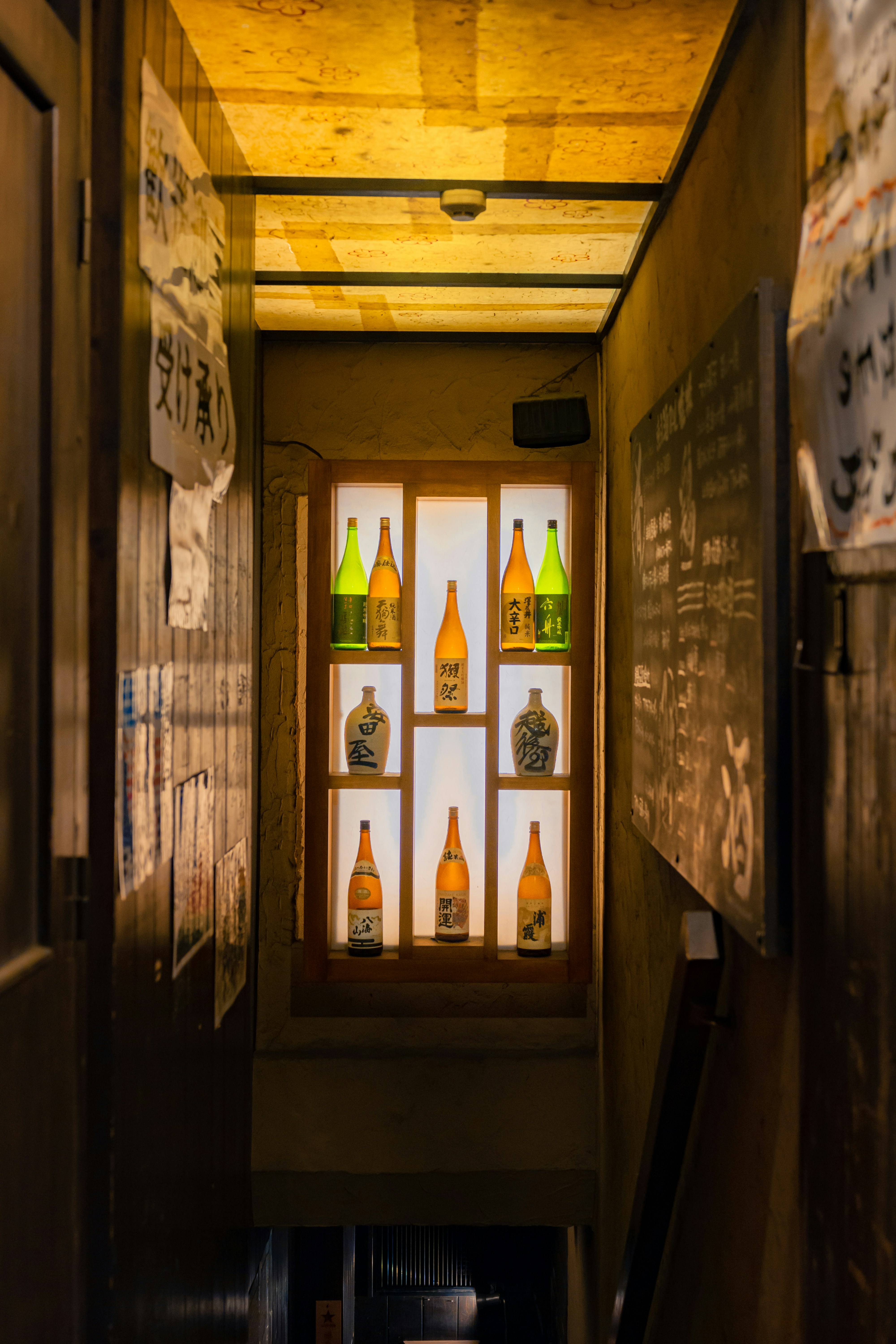 a hallway leading to a bar with bottles on the wall