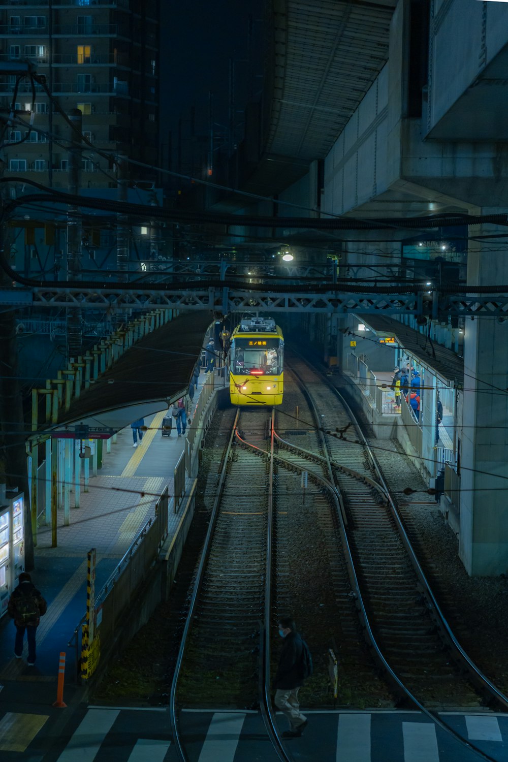 a yellow train traveling through a train station at night
