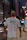 Close-up of a person in a white oversized t-shirt with striking black and red streetwear graphics, city skyline blurred behind.