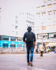 A traveler wearing headphones, walking through a vibrant city street with a phone in hand.