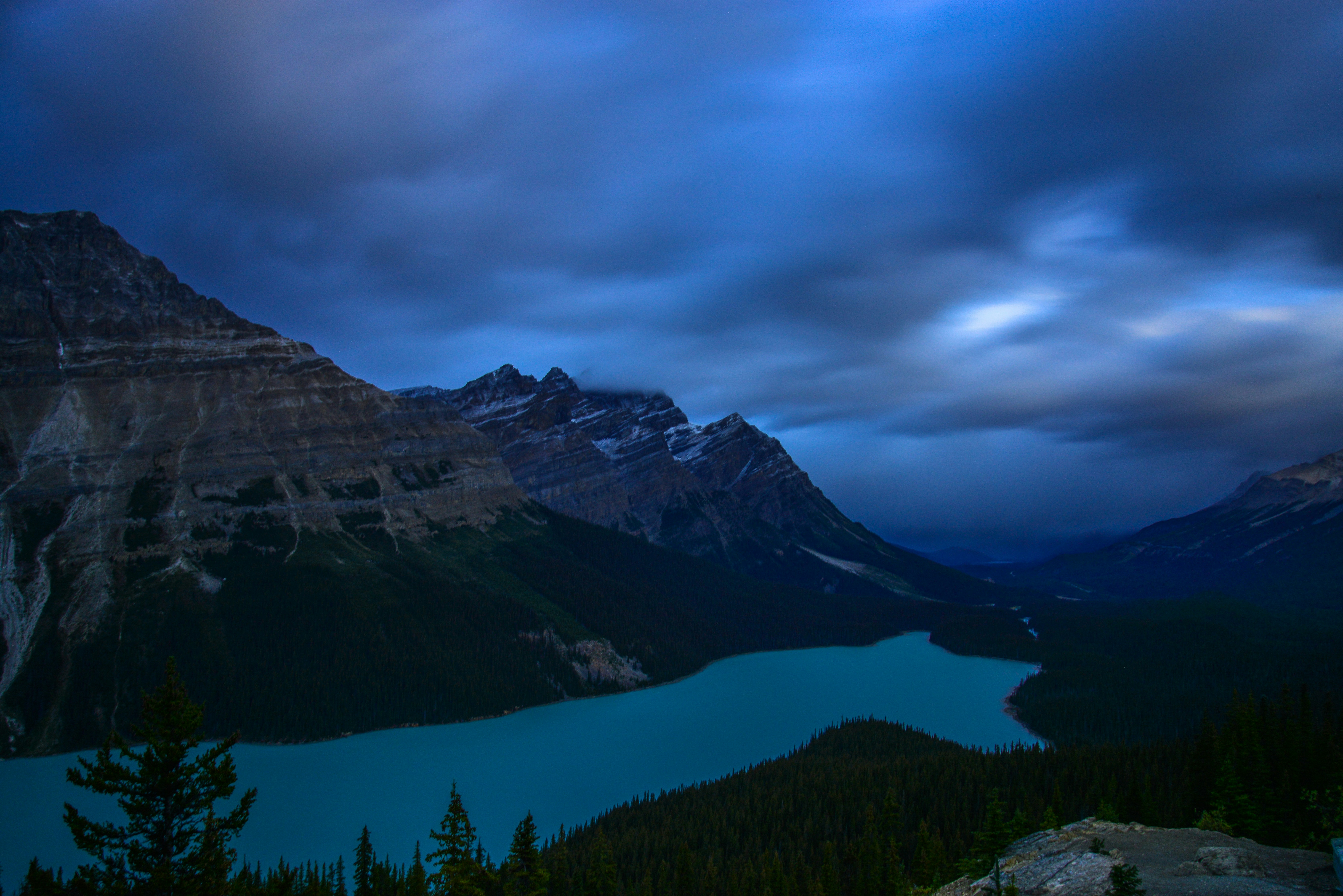 a lake surrounded by mountains under a cloudy sky