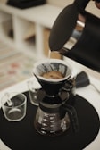 Hands carefully pouring hot water over coffee grounds in a pour-over setup.
