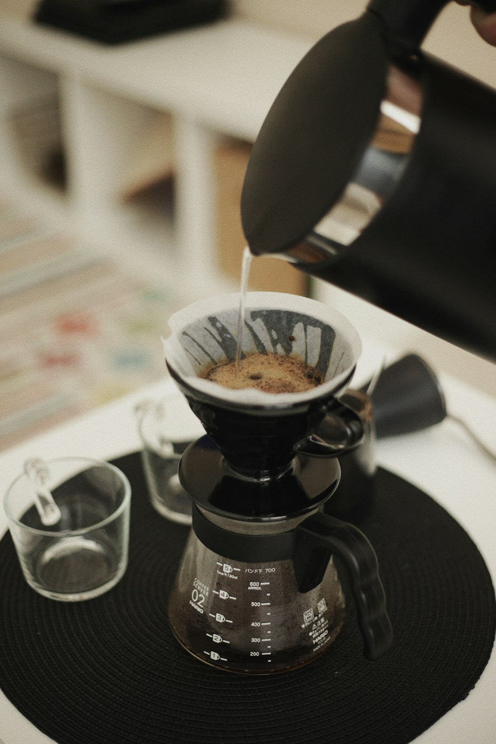 a person pours coffee into a glass cup