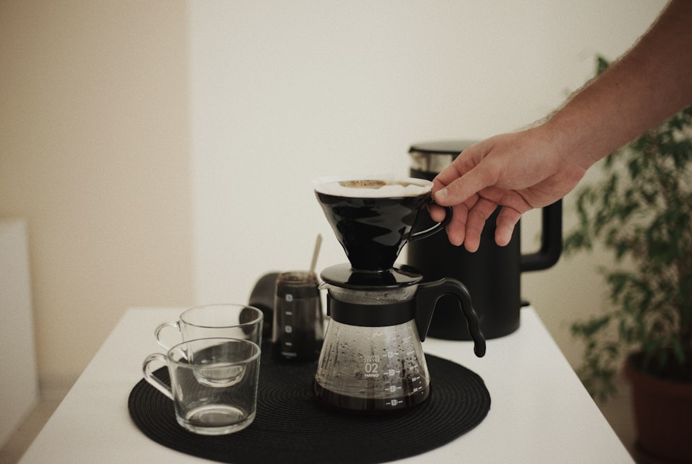 a person pours a cup of coffee from a coffee maker