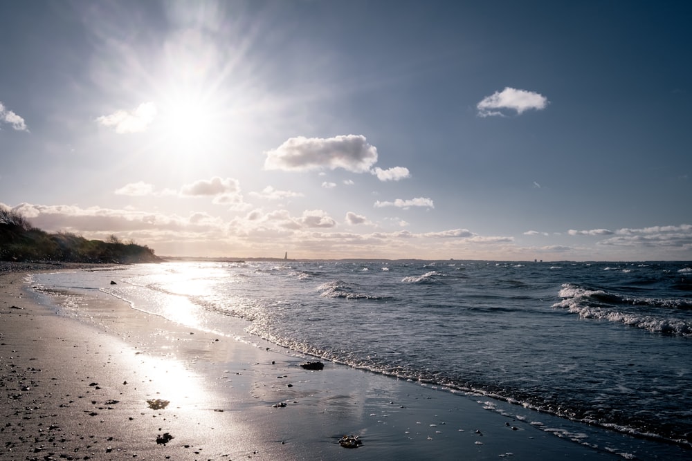 the sun is shining over the ocean on the beach