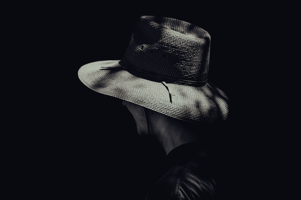 a black and white photo of a person wearing a hat
