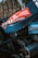 A close-up view of mechanical components of a vehicle featuring a prominent tire and engine parts. The vehicle sports a sticker with 'Dakar Classic' and 'Saudi Arabia' along with the number 707, suggesting participation in a rally event.