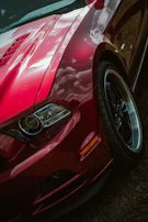 Close-up of a shiny red sports car's front grille and headlights.