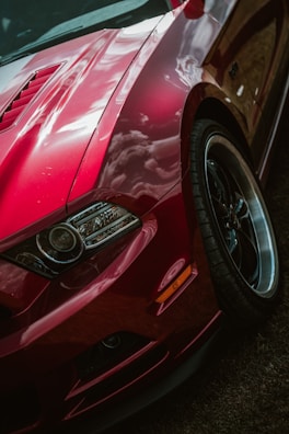 A close-up of a shiny, freshly detailed red sports car reflecting sunlight.