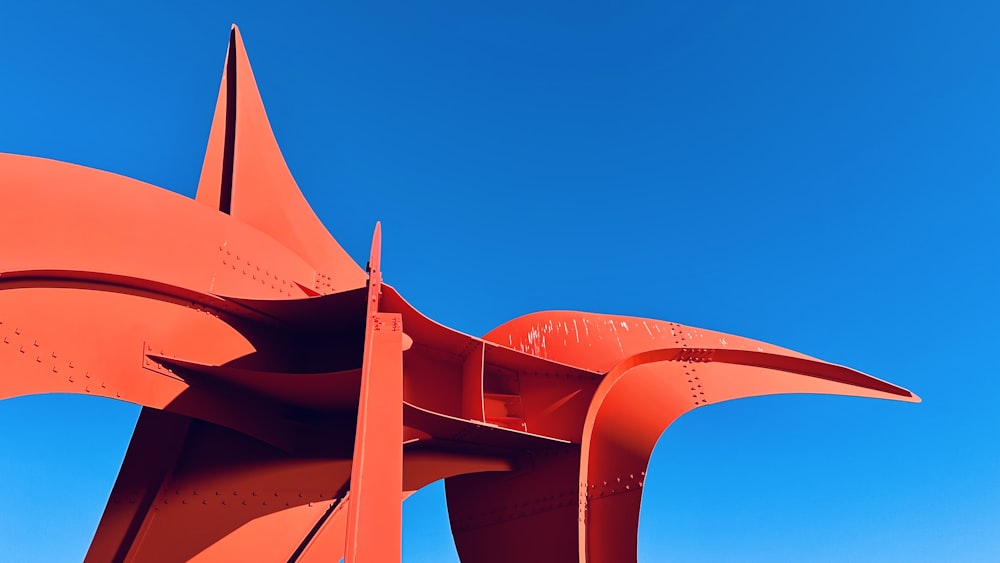 a large orange sculpture against a blue sky