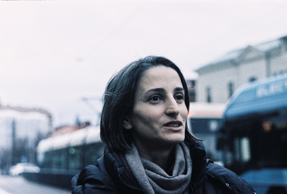 a woman standing in front of a bus on a city street