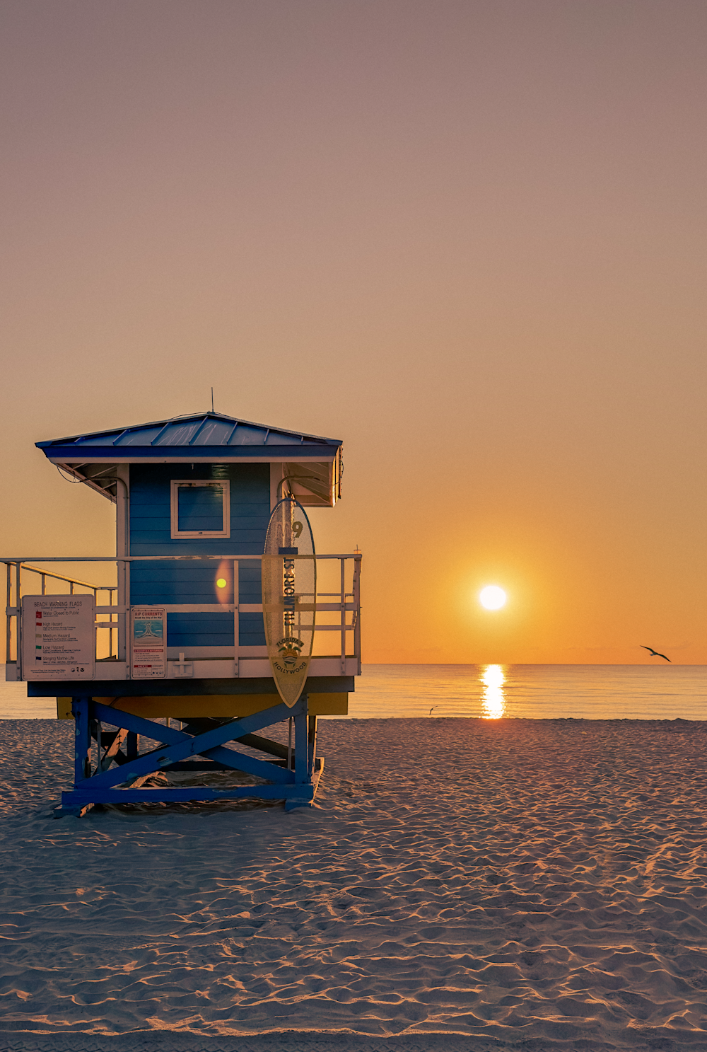 a lifeguard tower on a beach at sunset