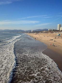 A sunny beach with calm waves and people enjoying the shore
